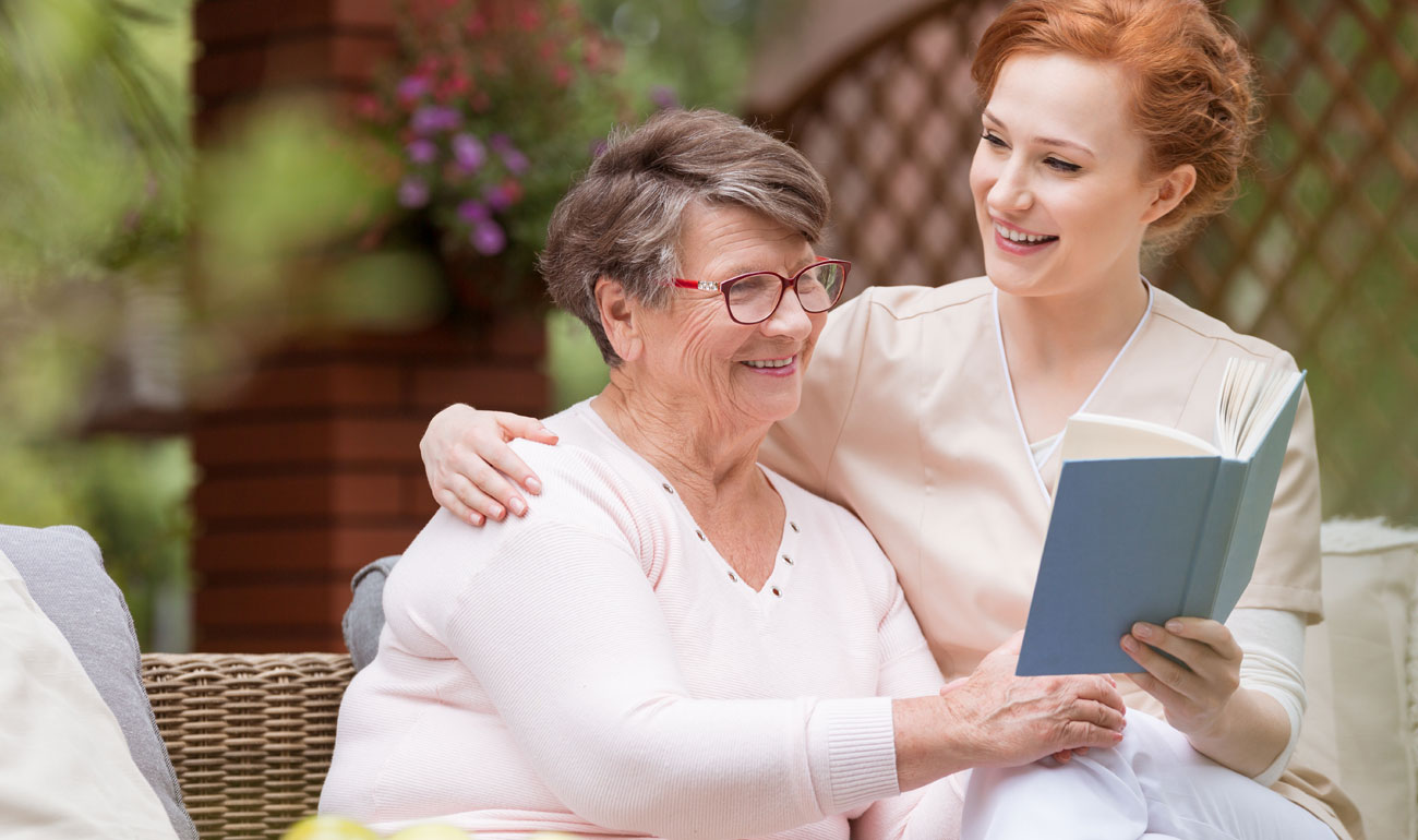 nurse reading book with elderly lady